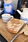 Cut loaf and knife on wooden board and blue and white ceramic crockery