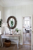 Console table with curved legs below mirror with sunburst frame on wooden wall