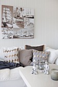 Coffee table in front of sofa with scatter cushions below photos printed on canvas on white, wood-clad wall