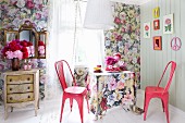 Floral wallpaper, matching tablecloth and pink, retro, metal chairs; peonies on vintage cabinet and vanity mirror to one side