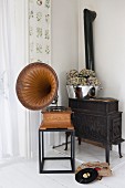 Old gramophone on side table in front of black iron stove in corner