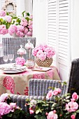 Table on terrace decorated with pink mophead hydrangeas