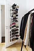 Partially visible clothes rack and white metal shoe rack mounted on door in dressing room