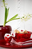 Miniature doughnuts in red glass bowl on table decorated with primula flowers & hyacinths
