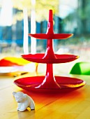 Bright red cake stand and small animal ornament on dining table