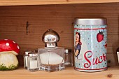 Various salt cellars and vintage sugar tin on wooden shelf