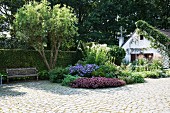 Paved drive leading to flowerbed and small house