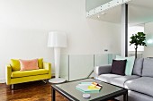 Lounge area with pale grey couch, yellow armchair and designer standard lamp