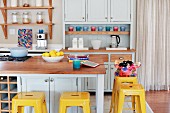 Yellow vintage bar stools at counter in pastel grey Shaker-style kitchen