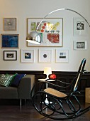 Retro arc lamp above Thonet rocking chair, Tulip table, , couch and gallery of artworks on wall above wainscoting