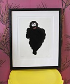 Michelin-man picture on yellow stool against mauve wallpaper