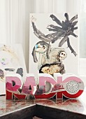 Red radio with housing shaped like word 'Radio' in front of child's drawing
