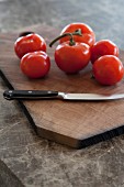 Tomatoes and knife on wooden chopping board