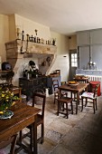 Rustic kitchen-dining room with wooden tables and chairs and antique wood-burning cooker in deep former fireplace