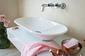 A designer console basin on a washstand with a glass surface and a wall tap