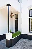 Front porch of traditional Dutch house with steel pillar, integrated planter and retro lantern