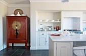 Blick über Küchenblock auf asiatischen Schrank in Wandnische und eingebauter weißer Küchenzeile im Landhausstil