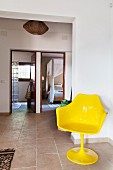 Gelber Tulpenstuhl in Diele mit Natursteinplatten; Blick durch offene Türen in Bad und Schlafraum im Hintergrund