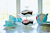Pale blue tea set and cupcakes on cake stand on table