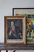 Gerahmtes Renaissance- Männerportrait und Vintage Filmposter auf rustikaler Holzbank