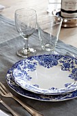 Vintage place setting with blue and white crockery and glasses on grey linen place mat