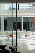 Essplatz mit Tulip Table und passenden Stühlen in weiss im Klassikerstil auf weißem Kunstharzboden in zeitgenössischer Architektur