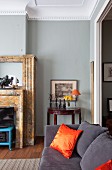 Dunkelgraue Polstercouch und orangefarbenes Seidennkissen in traditionellem Wohnzimmer mit grau getönter Wand