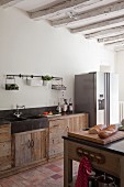Blick über Theke auf Küchenzeile, mit Massivholzunterschränken, seitlich moderner Kühlschrank aus Edelstahl