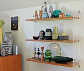 Collection of retro vases on wooden shelves supported by transparent plastic end panels