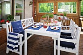 White table and chairs with blue seat cushions and place mats in Loggia