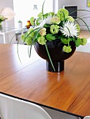 Hydrangeas and white dahlias in black designer vase on wooden table