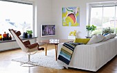 Sofa, Drehsessel und Retrotisch in skandinavischem Wohnzimmer; TV und modernes Bild im Hintergrund