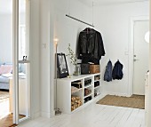 White hallway with open-fronted shoe rack, suspended coat rail and standard lamp in Scandinavian interior