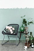 Hand-crafted cushion cover with photo print on tubular metal chair with woven seat next to collection of vintage bottles