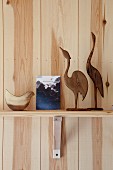 Wooden bird sculptures arranged on bracket shelf on pine wall