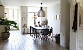 Designerlampe aus Birkenholz über Esstisch mit polierter Betonplatte und Schalenstühle im Esszimmer