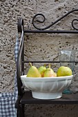 Pears in a bowl against a wall