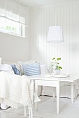 Sitzecke in weißem skandinavischen Wohnraum mit Sofa und Tisch mit klappbaren Seitenplatten