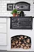 Black, cast iron oven integrated in masonry kitchen counter with firewood stored in niche below