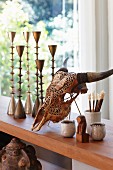 Animal skull next to collection of metal candlesticks on wooden surface