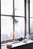 Stadtbild aus Papier an Fenster, Kerzen und Zapfen auf Fensterbank
