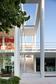 Glass façade of contemporary house with porch on pillars and terrace in background