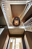 View up through stairwell with chandelier and white wooden balustrade