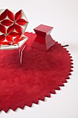 Designer armchair upholstered with 3D floral structure and red side table on round rug with zigzag edge