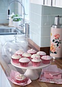 Decorated cupcakes in pink cases on white cake stand