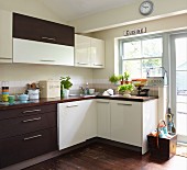 Pale and dark cabinet fronts in simple fitted kitchen with potted herbs and vintage-style lettering