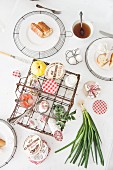 Top view of set breakfast table with various foodstuffs in vintage wire basket