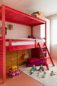 Wooden loft bed with ladder stained light red and toys on rug in child's bedroom