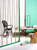 Green wooden frame strung with rope as partition, bench with fabric seat, lamp made from copper piping and rope