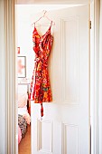 Buntes Sommerkleid an halboffener Tür zum Schlafzimmer